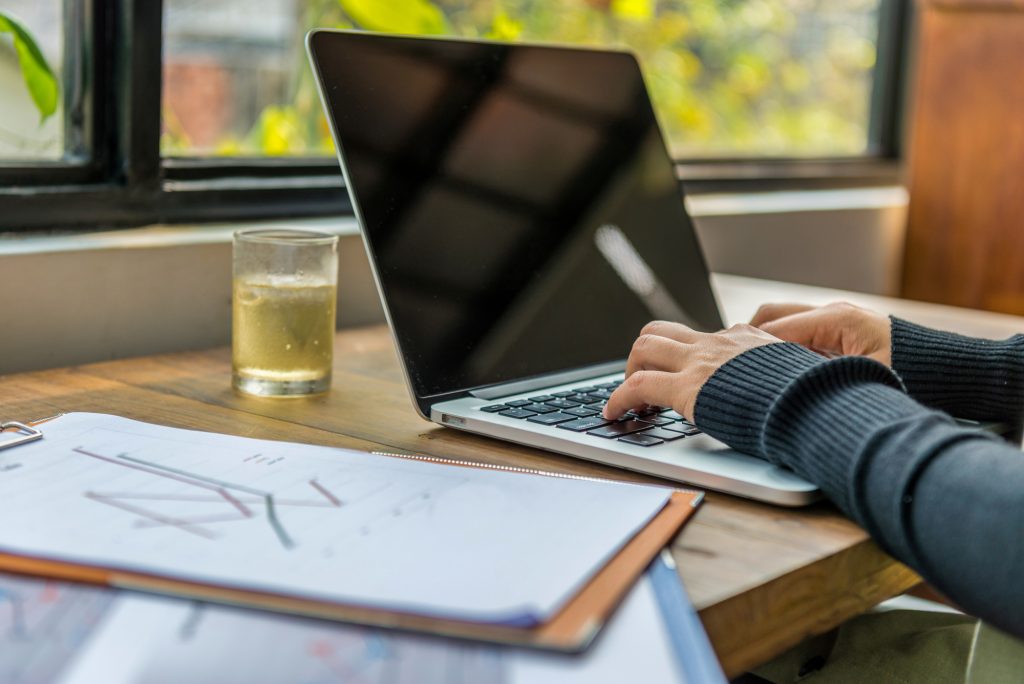An individual engaging in ethical considerations while ghostwriting for businesses on a laptop at a desk.
