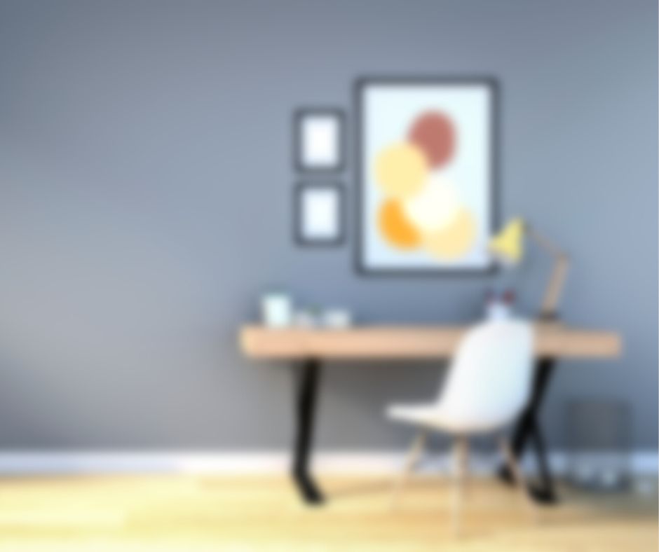 Blurry home office with a white chair and wooden desk in front of a blue wall 