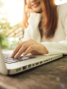 A woman typing on a laptop to boost your brand in business.